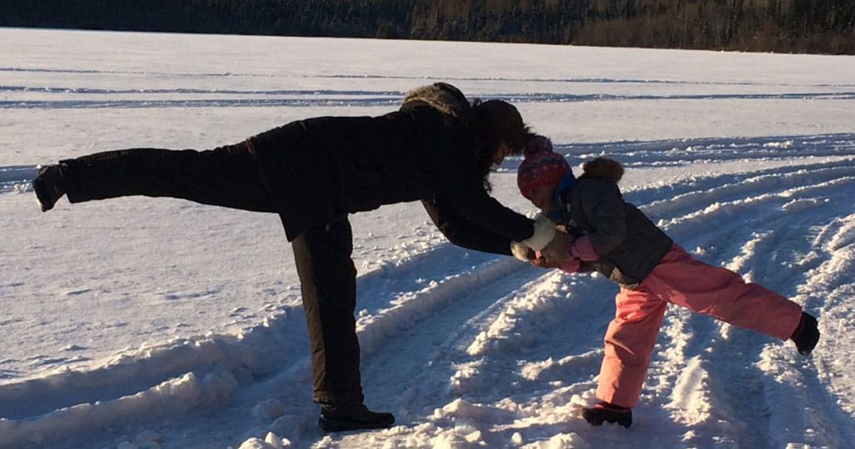 Femme et fillette faisant du yoga l'hiver, dans la neige